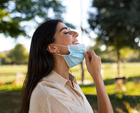 Woman breathing in air happily while pulling her face mask down